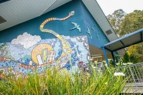 School building wall with a colourful illustrated mural and garden in front