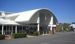 Modern school building with curved white roof and glass entrance under a clear blue sky.